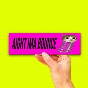 May include: A rectangular sticker with a bright pink background featuring the black text AIGHT IMA BOUNCE on the left side and a graphic of a brown and white cat head attached to a silver metal spring on the right side of the design.
