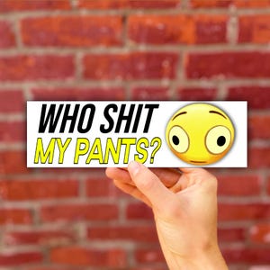May include: A rectangular sticker with a white background featuring the black text WHO SHIT and the yellow text MY PANTS? next to a yellow emoji face with wide, surprised eyes and a flat mouth, conveying a humorous and shocked expression.