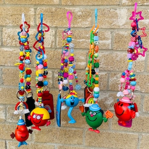 Puede incluir: Una colección de llaveros de cuentas coloridas con varios dijes y figuras de personajes. Los llaveros presentan una variedad de cuentas de diferentes formas y colores, incluyendo rojo, amarillo, azul y verde. Algunos llaveros tienen figuras de personajes.