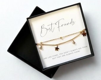 May include: A gold-colored, layered bracelet with star and crystal charms, presented in a black gift box. The card inside reads "Best Friends" with the quote "ARE LIKE STARS, YOU DON'T ALWAYS SEE THEM BUT THEY ARE ALWAYS THERE."