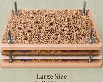 May include: A rectangular flower press made of light-colored wood with a laser-engraved botanical pattern on the top panel. It features four metal threaded rods at the corners with adjustable wing nuts and contains layers of cardboard and paper.