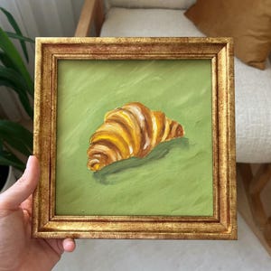 Pintura al óleo de croissant sobre fondo verde / Arte mural de cocina pequeño / Decoración de pastelería / Con o sin marco dorado / de LifeWingsArt