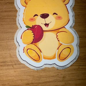 Sticker mignon ours en peluche - Ours kawaii tenant une pomme - Adorable autocollant en vinyle pour ordinateurs portables, journaux, bouteilles d'eau et plus
