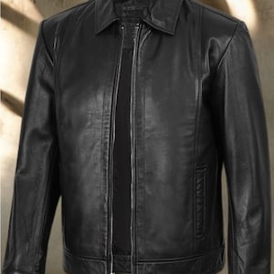 May include: A black leather jacket with a collared neckline and a full-length zipper closure. The jacket has a classic design with a tailored fit, featuring a small pocket on the chest and two side pockets. The jacket is made of a smooth, shiny leather material.