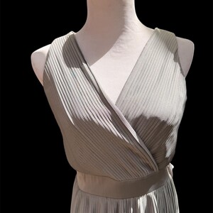 May include: A gray sleeveless dress with a V-neckline and a pleated skirt.