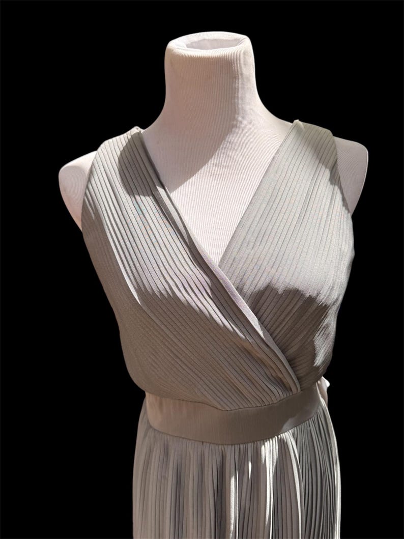 May include: A gray sleeveless dress with a V-neckline and a pleated skirt.