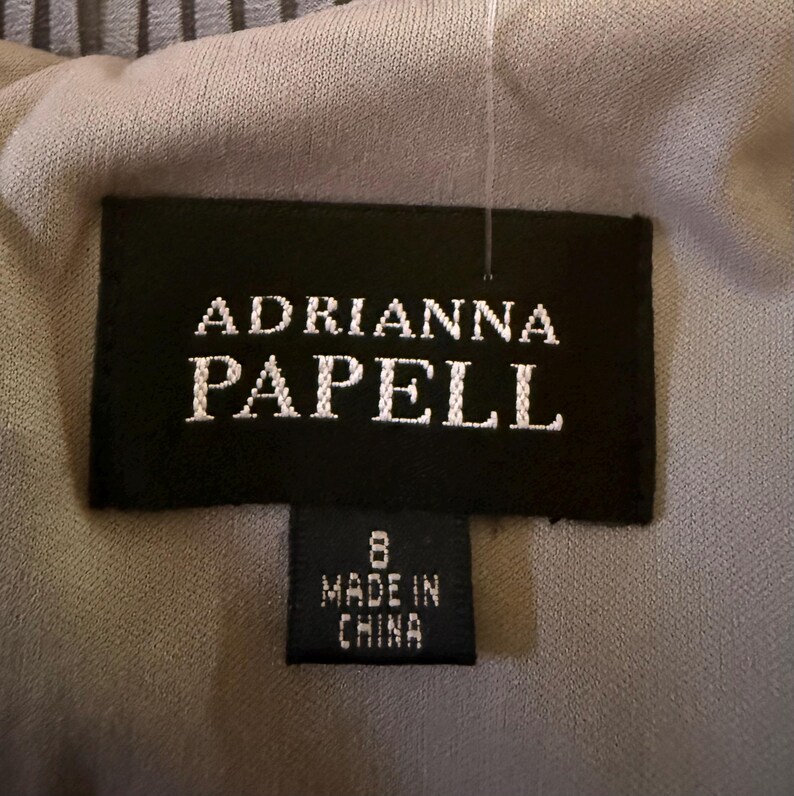May include: A black and white label with the text "Adrianna Papell" and a smaller label below that says "8 Made in China".