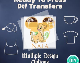 May include: Ready to press DTF transfers featuring a cartoon image of Nala from The Lion King in a Mickey Mouse ear design. The image is on a clear background with the text "Nala" below the image. The image is surrounded by a white border. The image is shown on a blue background with a white outline of a t-shirt, a baseball cap, a mug, and a DIY logo.