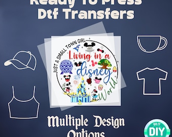 May include: A white design with the text "Just a small town girl living in a disney world" with a variety of Disney characters and icons. The design is on a clear background with a white border. The text "Ready to Press Dtf Transfers" is at the top of the image. The text "Multiple Design Options" is at the bottom of the image. The text "Do It Yourself" is in a green circle with a white background.
