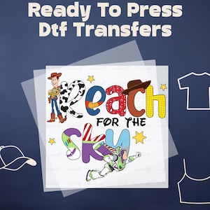 May include: Ready to Press DTF transfer featuring a colorful graphic of the words "Reach for the Sky" with cartoon characters Woody and Buzz Lightyear from the Toy Story movie franchise. The transfer is on a clear sheet and can be used to create custom apparel and accessories.