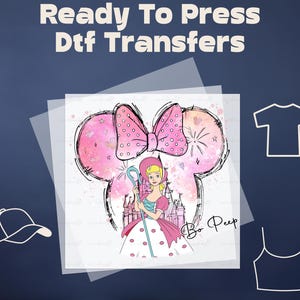 May include: A pink and white DTF transfer with a cartoon image of a girl with a pink bow and a shepherd's crook. The girl is standing in front of a castle with a pink and white watercolor background. The text "Bo Peep" is written in black at the bottom of the image.
