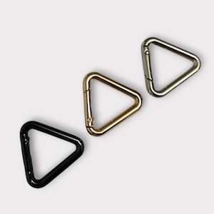 May include: Three triangle-shaped metal clasps in black, gold, and silver.