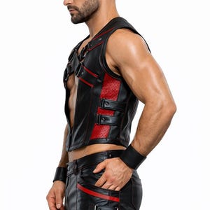 May include: Black leather vest with red accents, featuring a perforated panel and buckle details. Matching black leather shorts with red trim and buckle closures. A black leather wristband completes the ensemble.