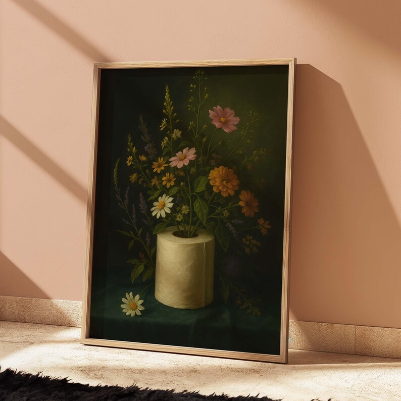 Puede incluir: Una impresi&oacute;n art&iacute;stica enmarcada que presenta un bodeg&oacute;n de flores coloridas en un jarr&oacute;n de rollo de papel higi&eacute;nico. Las flores incluyen margaritas, flores rosas y naranjas, y lavanda sobre un fondo verde oscuro. La obra de arte se muestra en un marco de madera clara.