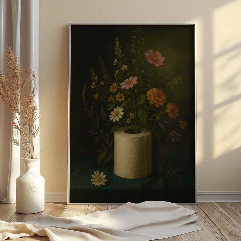 Puede incluir: Una pintura enmarcada de naturaleza muerta que presenta un ramo de flores coloridas en un rollo de papel higi&eacute;nico. Las flores, rosas, naranjas, amarillas y blancas, se destacan sobre un fondo verde oscuro. La obra se exhibe sobre un suelo de madera.