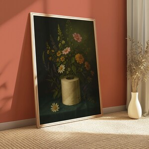 Puede incluir: Una impresi&oacute;n art&iacute;stica enmarcada que presenta una naturaleza muerta de flores coloridas dispuestas en un rollo de papel higi&eacute;nico. La obra de arte tiene un fondo oscuro y un marco dorado. Una sola margarita descansa sobre la superficie verde.