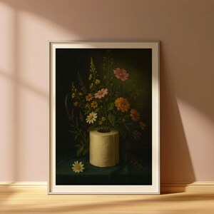 Puede incluir: Una impresi&oacute;n art&iacute;stica enmarcada que presenta una naturaleza muerta de flores coloridas dispuestas en un rollo de papel higi&eacute;nico. Las flores incluyen margaritas, cosmos y otras flores silvestres, sobre un fondo verde oscuro. La obra de arte se exhibe en una habitaci&oacute;n con una pared rosa y suelo de madera.