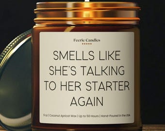 May include: A 9 oz amber glass jar candle with a gold lid and a white label. The label features the text Feerie Candles with five stars and the phrase SMELLS LIKE SHE'S TALKING TO HER STARTER AGAIN, followed by 9 oz | Coconut Apricot Wax | Up to 50 Hours.