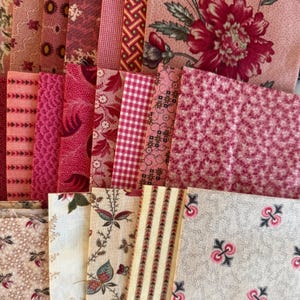 May include: A selection of pink and red fabric samples featuring diverse patterns, such as floral, gingham, and geometric motifs. The fabrics are arranged in a layered display, highlighting a variety of textures and hues. The colour scheme is primarily composed of pink and red tones.