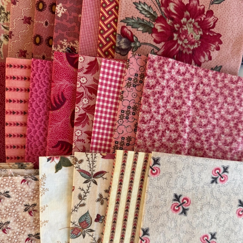 May include: A selection of pink and red fabric samples featuring diverse patterns, such as floral, gingham, and geometric motifs. The fabrics are arranged in a layered display, highlighting a variety of textures and hues. The colour scheme is primarily composed of pink and red tones.