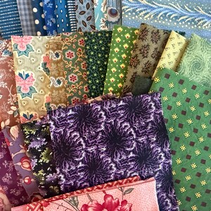 May include: A selection of fabric swatches in diverse colours and patterns. The fabrics feature floral, geometric, and paisley designs in shades of blue, green, purple, and pink. The swatches are arranged in a layered, overlapping composition.