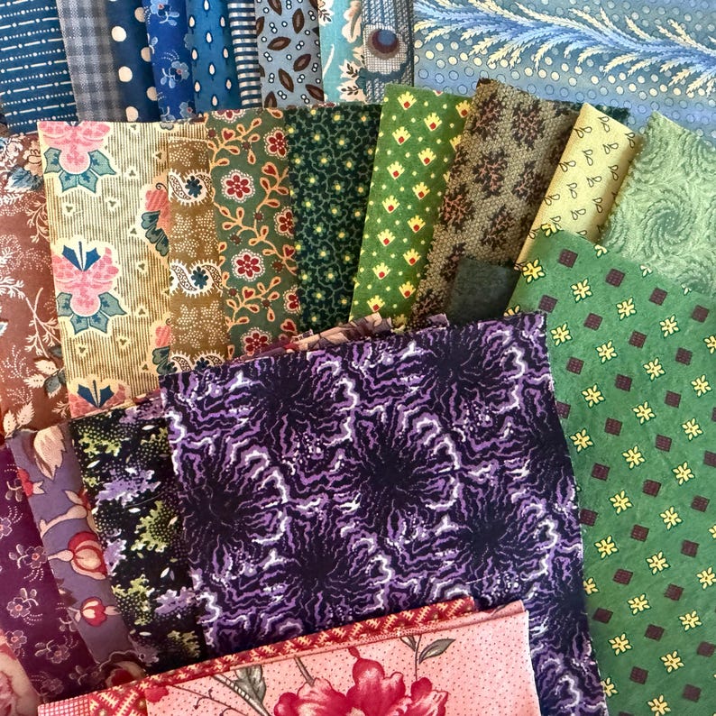 May include: A selection of fabric swatches in diverse colours and patterns. The fabrics feature floral, geometric, and paisley designs in shades of blue, green, purple, and pink. The swatches are arranged in a layered, overlapping composition.