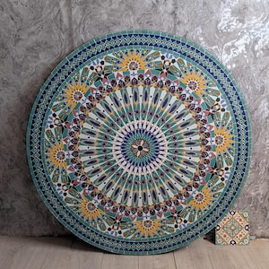 May include: A large, round mosaic table with a detailed geometric pattern in shades of teal, yellow, blue, and maroon. A small, square tile with a matching design sits beside it. The table is approximately 122 cm in diameter.