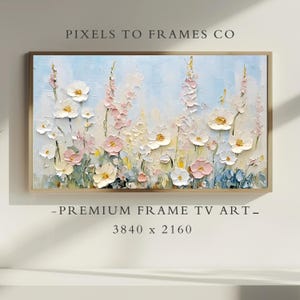 以下が含まれることがあります： 淡い青色の背景に、額装された花の絵画。白い、ピンク、黄色の花が、テクスチャのある筆致で描かれています。フレームは薄茶色です。上部のテキストは「PIXELS TO FRAMES CO」と書かれています。