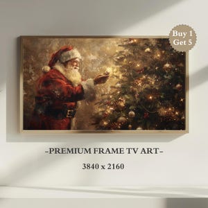 May include: A framed artwork depicts Santa Claus decorating a Christmas tree with lights and ornaments. Santa is wearing a red suit and hat. The artwork has a gold frame and the text "-PREMIUM FRAME TV ART-" and "3840 x 2160" are visible.