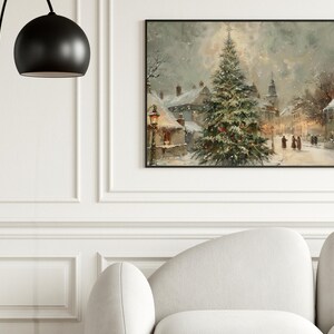 Peut inclure: Une peinture encadr&eacute;e d'un paysage hivernal repr&eacute;sente une place de ville enneig&eacute;e avec un sapin de No&euml;l d&eacute;cor&eacute;. L'&oelig;uvre pr&eacute;sente une palette de couleurs douces de blancs, de verts et de bruns, avec des personnages se promenant dans une rue enneig&eacute;e.