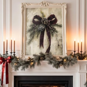 May include: A decorated fireplace mantel with a framed painting featuring a burgundy bow and pinecone. The mantel is adorned with a garland, candles, and a red bow. The painting is in a white ornate frame.