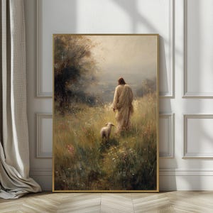 Può includere: Una stampa incorniciata raffigura una figura in una veste fluente che cammina attraverso un campo di erba alta, seguita da un agnello. L'opera d'arte ha una tavolozza di colori tenui e smorzati con una cornice dorata, evocando pace e serenità.