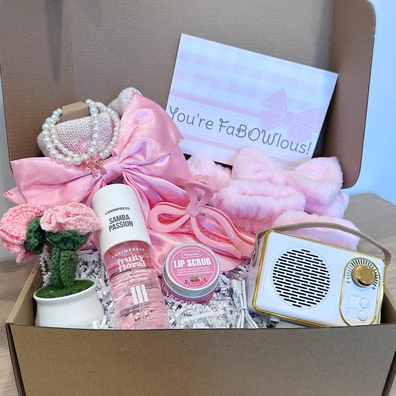 Pu&ograve; includere: Una confezione regalo rosa piena di oggetti, tra cui una collana di perle, un fiocco di raso, uno spray Samba Passion fruity floral, uno scrub per le labbra, una radio bianca e dorata e un fiore all'uncinetto. La carta dice "You're FaBOwlous!"