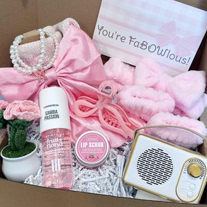 Pu&ograve; includere: Una confezione regalo piena di accessori e prodotti di bellezza rosa. Gli articoli includono un fiocco, accessori per capelli, una piccola radio, uno spray Samba Passion fruity floral e uno scrub per le labbra. Sono inclusi anche un fiore all'uncinetto e una carta con la scritta "You're FaBOwlous!".