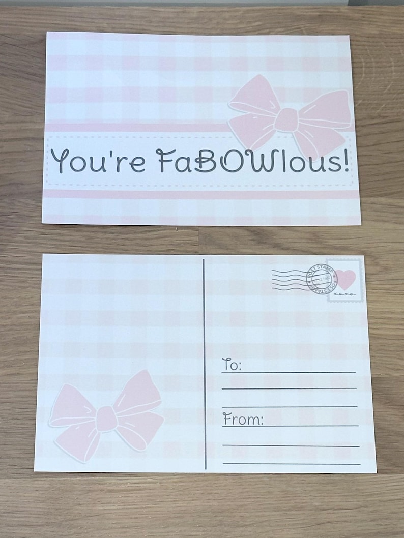 Pu&ograve; includere: Due cartoline con un motivo a quadretti rosa e bianco. Una carta ha un fiocco rosa e la scritta "You're FaBOwlous!". L'altra carta ha un fiocco rosa, le righe per "A:" e "Da:" e un francobollo.