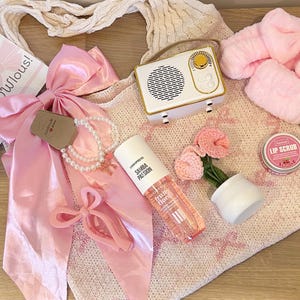 Pu&ograve; includere: Una collezione di oggetti rosa e bianchi, tra cui una radio, un fiocco, una collana di perle, una bottiglia di Samba Passion, un piccolo vaso con fiori rosa, uno scrub per le labbra e una borsa tote. Il testo "You're fabulous!" &egrave; visibile.