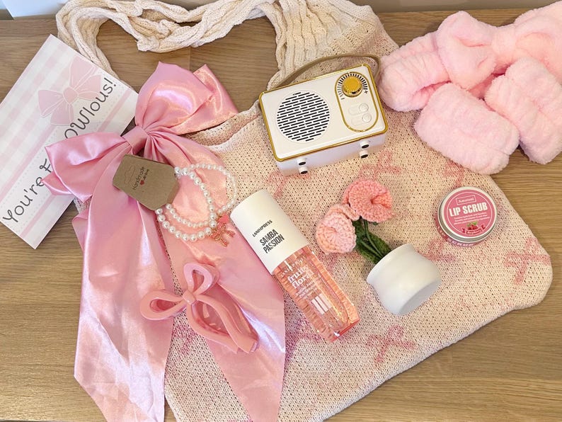 Pu&ograve; includere: Una collezione di oggetti rosa e bianchi, tra cui una radio, un fiocco, una collana di perle, una bottiglia di Samba Passion, un piccolo vaso con fiori rosa, uno scrub per le labbra e una borsa tote. Il testo "You're fabulous!" &egrave; visibile.