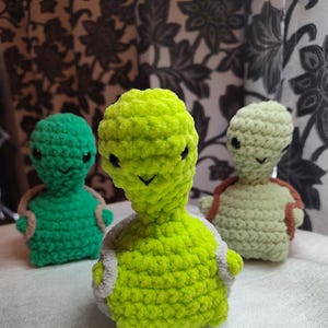 May include: Three crocheted turtle toys. One is green, one is light green, and one is light beige.