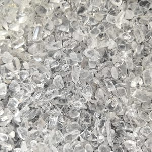 May include: A close-up view of a pile of small, clear quartz crystals. The crystals are irregularly shaped and have a translucent appearance.