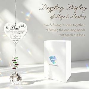 May include: A heart-shaped crystal suncatcher with the word "Dad" and a sentimental message. The suncatcher hangs from a silver chain and features colorful crystals and a large, clear crystal ball. A white box with a diamond logo is also in the image.