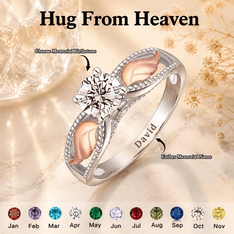 May include: A silver ring with a large, clear gemstone center and leaf-shaped accents. The ring has the text "David" engraved on the band. The image also shows a selection of birthstones and the text "Hug From Heaven".
