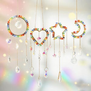 Può includere: Quattro acchiappasole sospesi a forma di cerchio, cuore, stella e mezzaluna. Ognuno ha una cornice dorata ed è decorato con perline colorate. Pendenti e catene di cristallo trasparente pendono sotto.