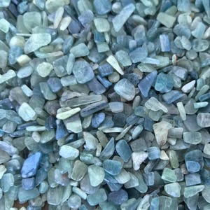 Peut inclure: Gros plan sur une collection de petites pierres bleues-vertes roulées. Les pierres sont de formes et de tailles variées, avec une finition lisse et polie.
