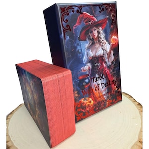 Może przedstawiać: Talia kart Tarot of Destiny z pudełkiem z ilustracją wiedźmy. Pudełko i krawędzie kart są czerwone. Wiedźma ma na sobie czerwony kapelusz i suknię, trzyma kociołek i świecącą kulę. Widoczny jest tekst "Tarot of Destiny".