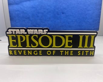 Pode incluir: Um logotipo preto e amarelo de Star Wars Episódio III: A Vingança dos Sith em um fundo branco.