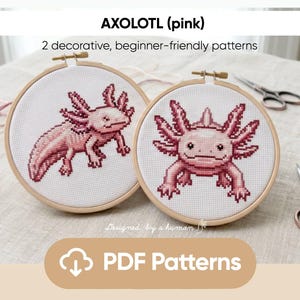 Könnte beinhalten: Zwei Kreuzstichmuster von rosa Axolotln in Holzreifen. Der Text "AXOLOTL (pink)" und "2 dekorative, anfängerfreundliche Muster" sind über den Reifen zu sehen. Die Worte "PDF Patterns" sind ebenfalls sichtbar.
