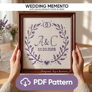 Könnte beinhalten: Ein gerahmtes Kreuzstich-Hochzeitsandenken mit dem Text "WEDDING MEMENTO" und "with personalized initials & date". Das Design umfasst die Initialen "A&C", das Datum "11.03.2026", ein Herz und einen floralen Kranz. Der Rahmen hat den Text "PDF Pattern".