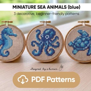 Könnte beinhalten: Drei Miniatur-Kreuzstichmuster von Meeresbewohnern in Blautönen: ein Seepferdchen, ein Oktopus und eine Schildkröte. Die Designs sind in hölzernen Stickrahmen dargestellt. Der Text "MINIATURE SEA ANIMALS (blue)" und "PDF Patterns" ist ebenfalls sichtbar.