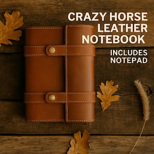 Puede incluir: Un cuaderno de cuero marrón con un diseño cosido y detalles en latón. El cuaderno incluye un bloc de notas y dice "Crazy Horse Leather Notebook" e "Includes Notepad".