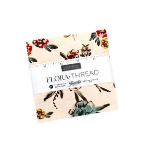 May include: A stack of square fabric swatches featuring a cream background with a floral pattern in red, teal, and mustard yellow. A white paper band wraps around the center, printed with "FLORA+THREAD" and a ruler measuring up to 9 inches.